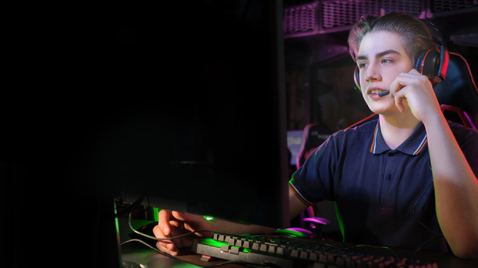 A gamer wearing a headset in front of a monitor. Blue light emission is 76% for conventional monitors, while it is 46% for OLED, emphasizing that OLED display emits up to 39% less harmful blue light.