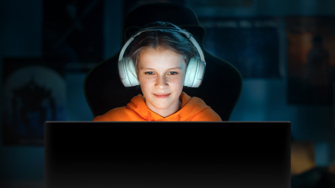 A girl playing a game in a dark room. Highlighting how OLED displays offer the best image quality without causing glare and allows comfort for the eye in any environment.